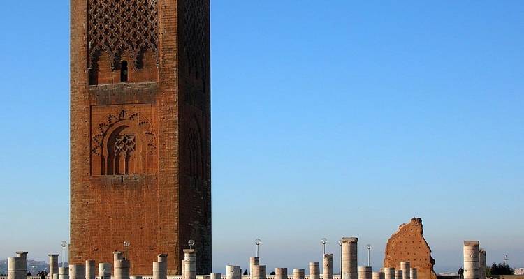 Minaret de la Tour Hassan en brique rouge s'élevant au-dessus de rangées de colonnes en marbre sous un ciel dégagé