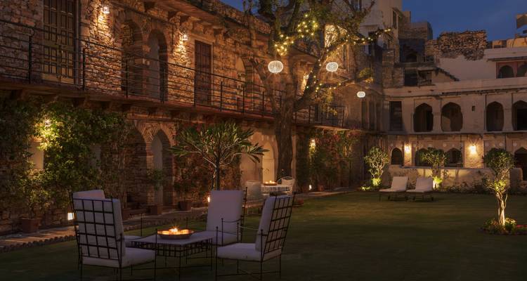 Scène récurrente de cour intérieure la nuit avec arbres illuminés, chaises et ambiance chaleureuse
