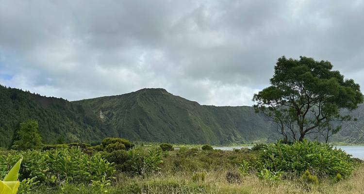 A tranquil crater lake bordered by green hills and low cloud cover on São Miguel.