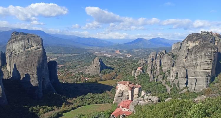 Panorama classique de Meteora avec plusieurs monastères perchés au sommet de colonnes rocheuses spectaculaires sur un ciel dégagé.