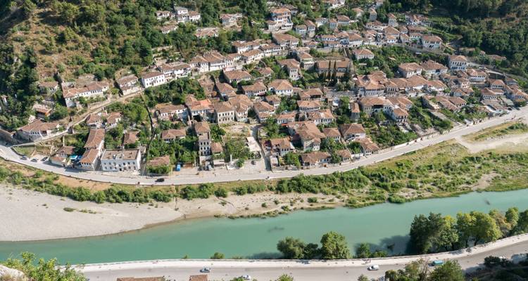 Luftaufnahme der historischen Bergstadt Berat mit Terrakottadächern entlang eines türkisfarbenen Flusses