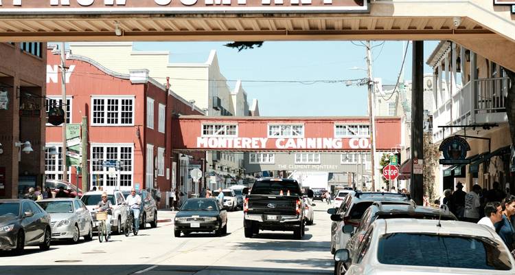 La rue animée de Cannery Row bordée de bâtiments de conserverie rouges et de voitures à Monterey.
