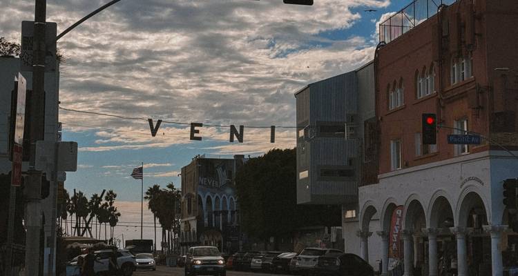 Panneau lumineux iconique VENICE au-dessus de l'avenue Pacific avec des piétons et des voitures en dessous.