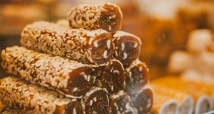 Pile de rouleaux de loukoum couverts de noix exposés dans un étal de marché