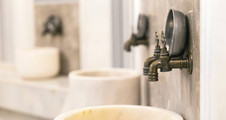 Close-up van sierlijke koperen kranen en marmeren wastafels in een traditioneel hammam.