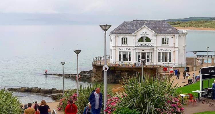 Café et galerie d'art Seafront Arcadia Beach sur pilotis à Portrush avec des visiteurs à proximité