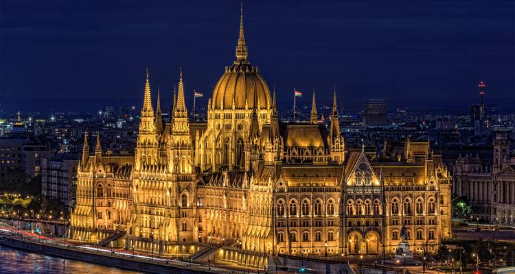 El edificio del Parlamento húngaro iluminado reflejándose en el Danubio por la noche