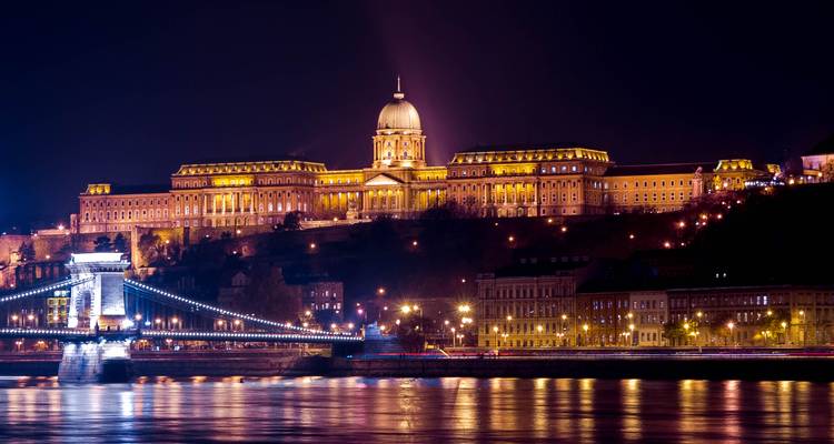 Panorama nocturna del Castillo de Buda y el Puente de las Cadenas brillando sobre el Danubio