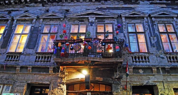 Decoraciones coloridas de balcón en la fachada de un pub-ruina desgastado en Budapest al atardecer