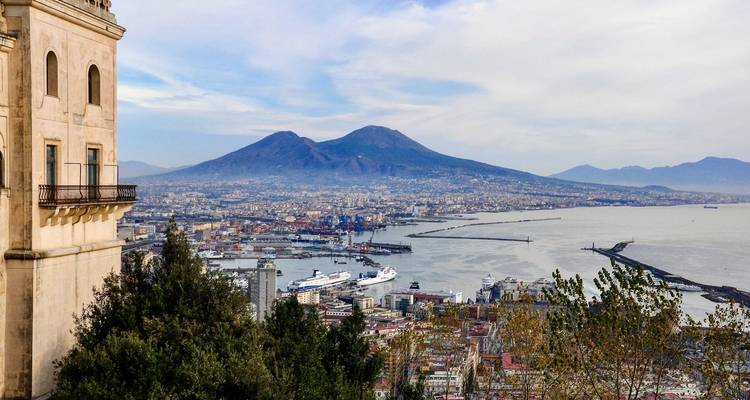 Panoramisch uitzicht over de haven van Napels met cruiseschepen en de Vesuvius die de skyline domineert.