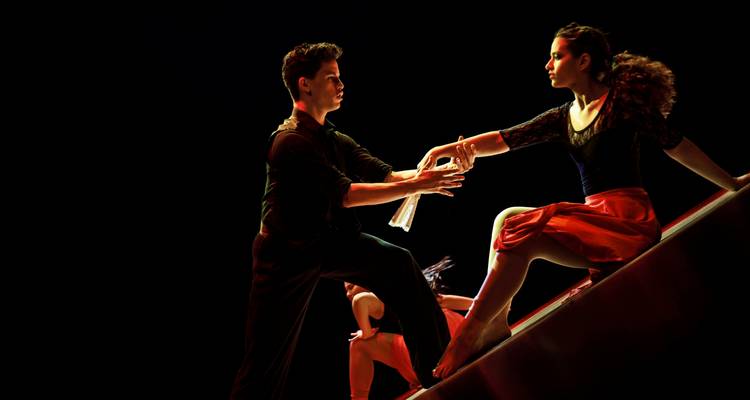 Représentation théâtrale stylisée de danseurs de tango illuminés sous un éclairage dramatique.