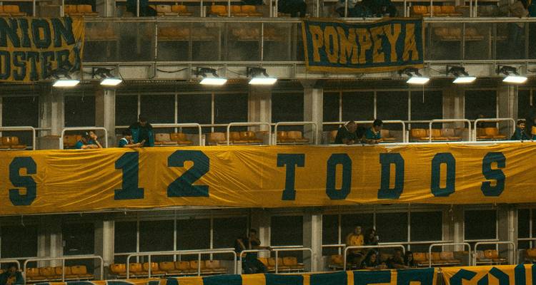 Section du stade de Boca Juniors avec une bannière jaune et des supporters enthousiastes.