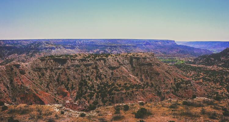 Vue panoramique sur les falaises et les mesas rouge-brun accidentées du Palo Duro Canyon sous un ciel dégagé