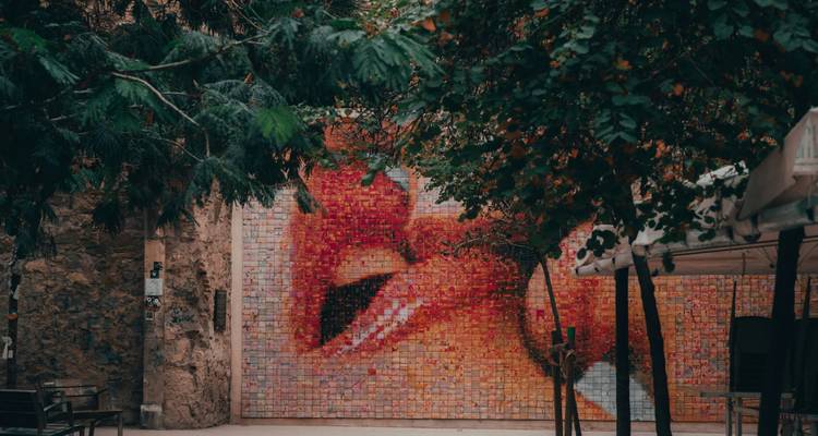 Mur en mosaïque extérieure représentant des lèvres qui s'embrassent dans une cour verdoyante
