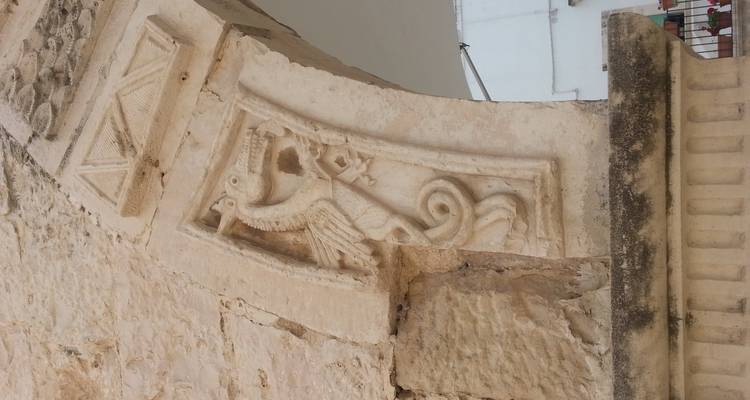 Gros plan d'un bas-relief en pierre médiéval représentant une créature ressemblant à un dragon sur une arche