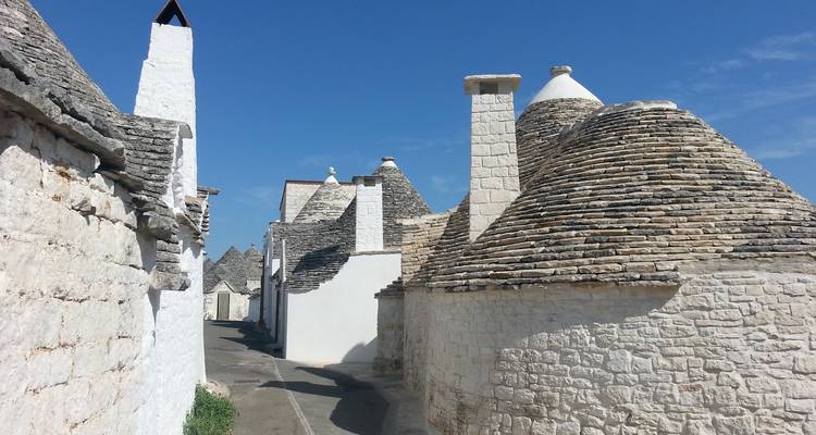 Rangée de maisons trulli traditionnelles longeant une ruelle étroite sous un ciel bleu dégagé