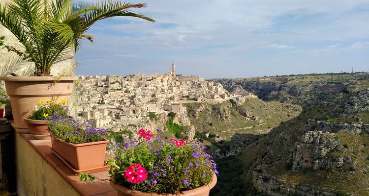Vue panoramique époustouflante sur la cité en pierre ancienne de Matera depuis une terrasse ornée de pots de fleurs colorés