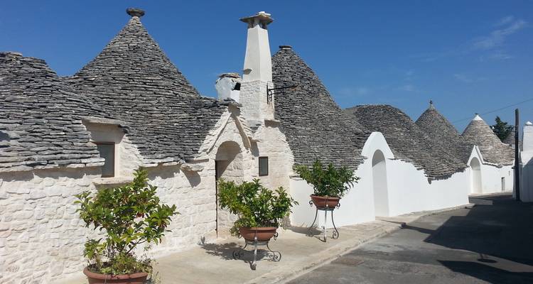 Rangée bien alignée de trulli aux toits en pierre pointus et aux murs blanchis à la chaux par une journée ensoleillée