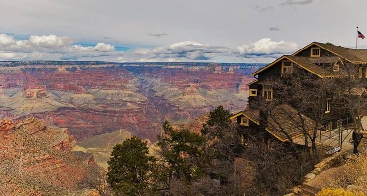 Lodge historique perché au bord du canyon offrant une vue imprenable sur les vastes paysages du Grand Canyon sous un ciel nuageux.