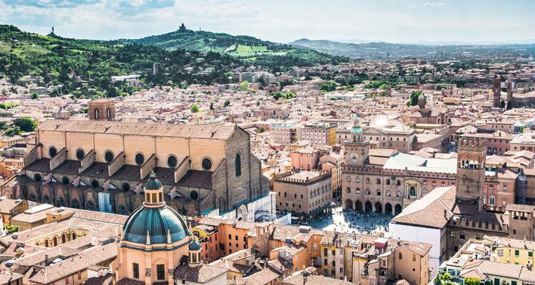 Verhoogd uitzicht op Bologna's historische centrum met de Basilica di San Petronio en rollende groene heuvels daarachter.