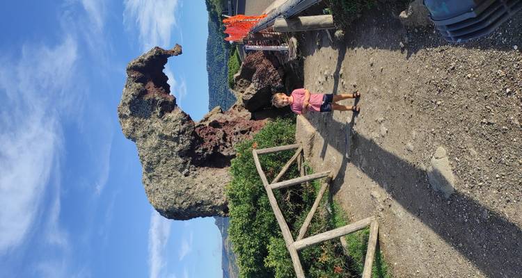 Un jeune enfant se tient devant la célèbre formation rocheuse volcanique en forme d'éléphant sous un ciel d'un bleu éclatant.
