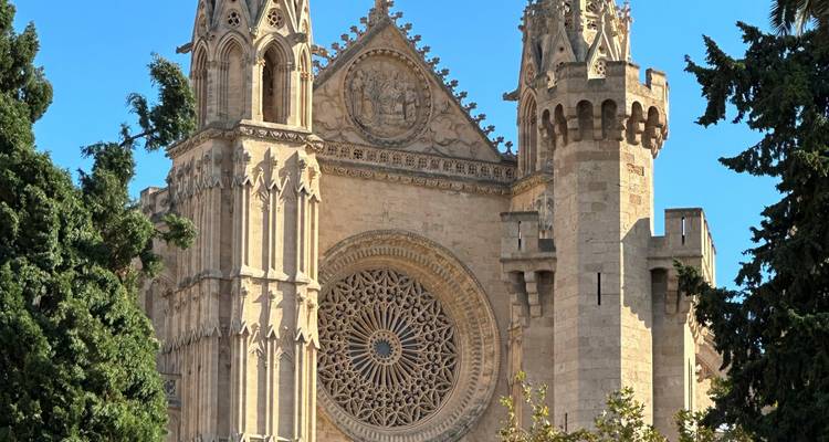 Façade d'église néo-gothique élaborée avec une rosace ornementée et des tours crénelées se détachant sur un ciel dégagé.