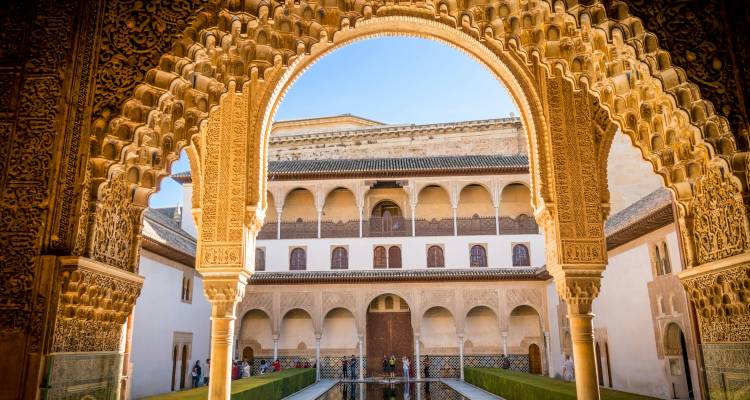 Une arche mauresque complexe encadre la cour sereine des Myrtes à l'Alhambra de Grenade.