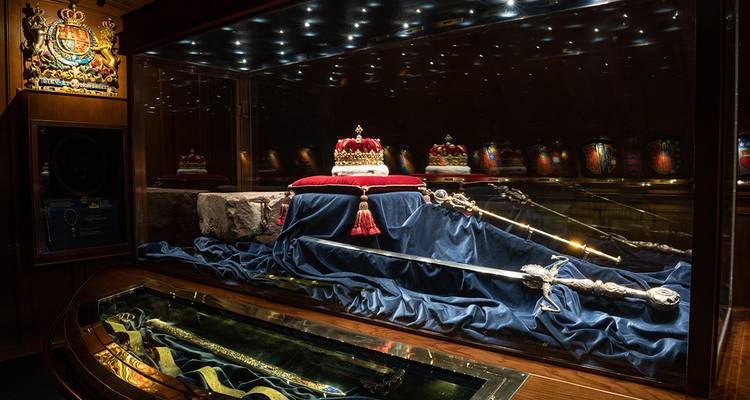Vitrine d'exposition des Joyaux de la Couronne écossaise avec épée ornée, sceptre et couronne sous projecteurs.