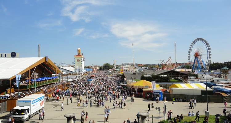 Massive Menschenmengen füllen das festliche Oktoberfest-Gelände mit Fahrgeschäften, Bierhallen und einem Riesenrad.