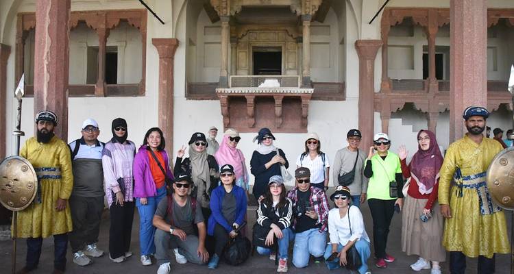 Gran grupo de turistas y guardias se reúnen para una foto dentro de un palacio histórico ornamentado