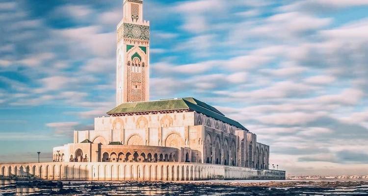De Hassan II-moskee torent uit boven de Atlantische Oceaan met zachte wolken die langs de hemel strijken.