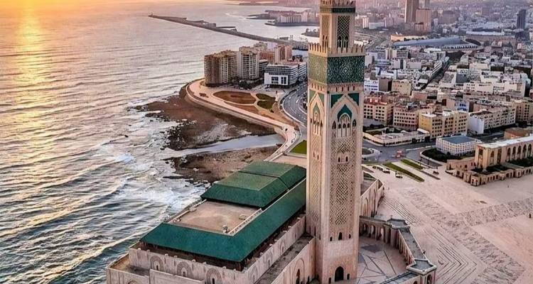 Luchtfoto van zonsondergang van de Hassan II-moskee die uittorent naast de Atlantische kustlijn en de stad Casablanca