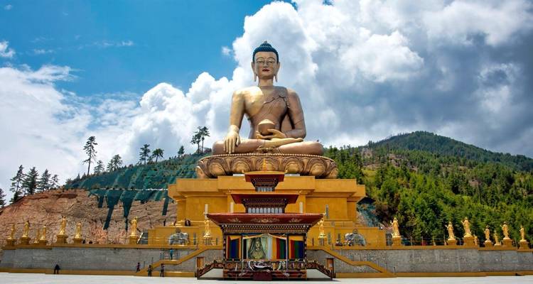 Massive goldene Buddha-Statue Dordenma, die sich vor dramatischen Wolken und bewaldeten Hügeln erhebt.