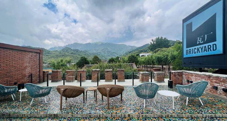 Terrasse extérieure de The Brickyard avec sol en mosaïque, chaises design et vues sur les montagnes au-delà.