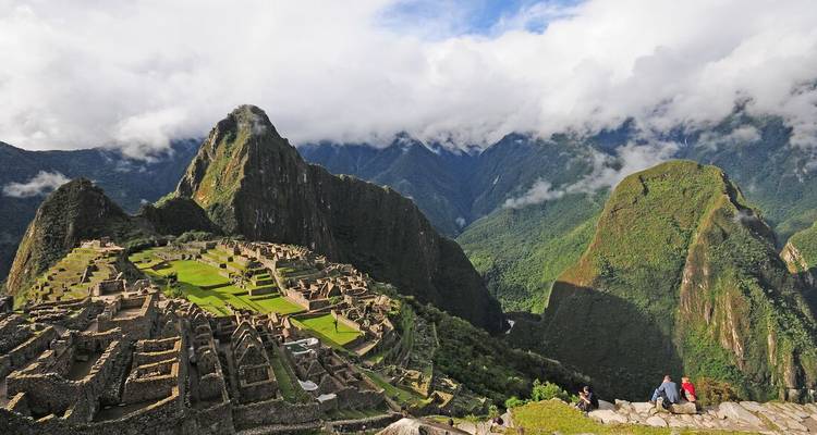 Vista panorámica de las ruinas de Machu Picchu con montañas verdes impresionantes y nubes bajas.