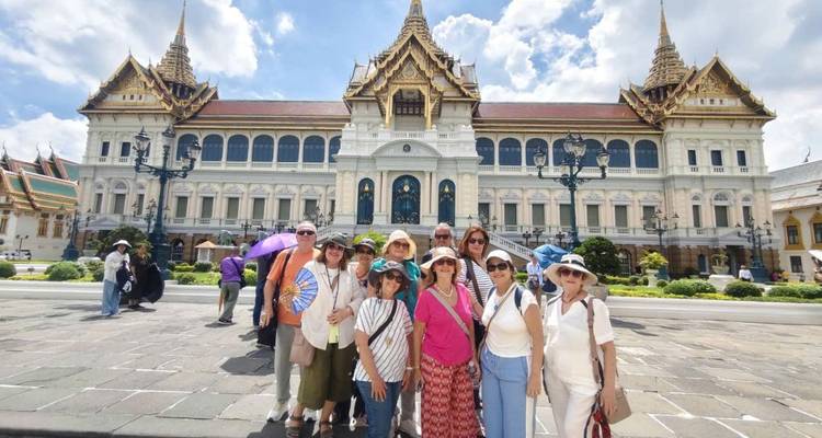 Le groupe de touristes pose devant le complexe du Grand Palais de Bangkok sous un brillant soleil.