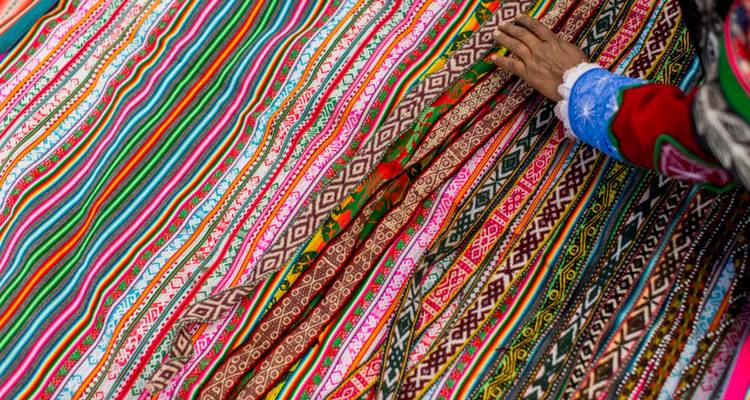 Gros plan de la main d'un tisserand touchant des motifs de textiles andins vibrants aux couleurs éclatantes
