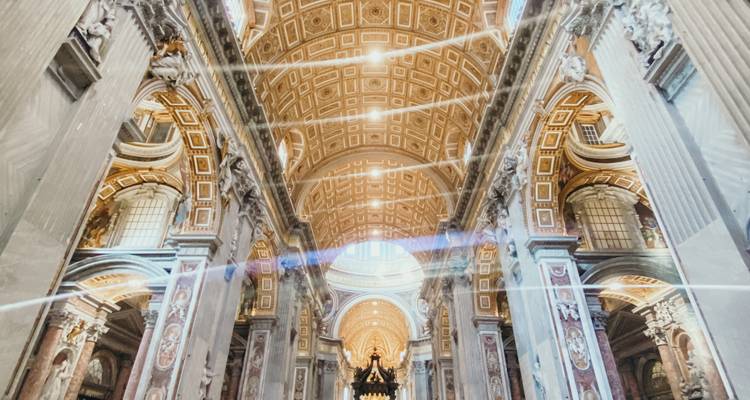Luxe interieur van de Sint-Pietersbasiliek met een gemusterd gouden plafond en dramatische lichtstralen.