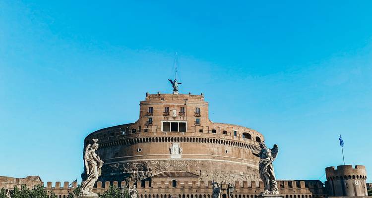 Castel Sant'Angelo omlijst door beelden tegen een levendige blauwe hemel.