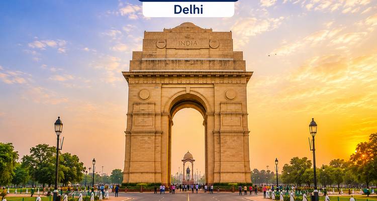 India-Gate-Denkmal bei Sonnenaufgang mit warmem goldenen Himmel; große Textbezeichnung "Delhi" erscheint oben im Bild.