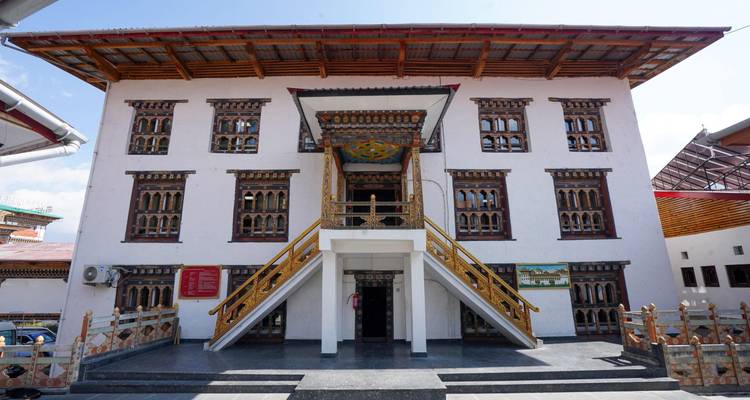 Front view of a traditional Bhutanese museum building with ornate wooden windows and clear blue sky.