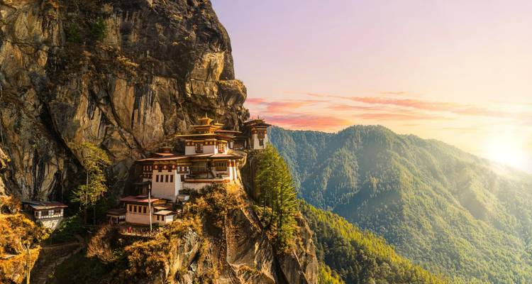 Sunset light bathes Tiger’s Nest monastery hanging on a rugged cliff with expansive mountain backdrop.