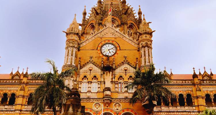 Primer plano de la fachada ornamentada de la torre del reloj de la Estación Terminal Chhatrapati Shivaji contra un cielo despejado.