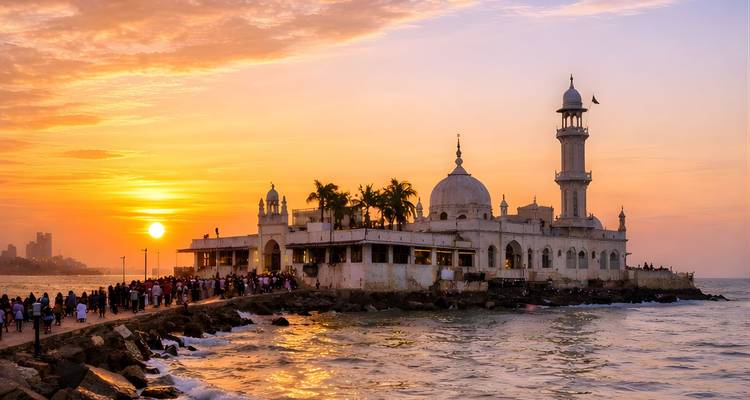 Las multitudes caminan por la calzada hacia la mezquita Haji Ali Dargah durante una puesta de sol oceánica vibrante.