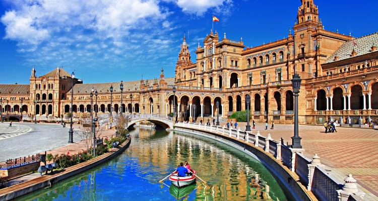 Het prachtige Plaza de España met zijn boogbruggen en kanaal schittert onder een levendige blauwe hemel.