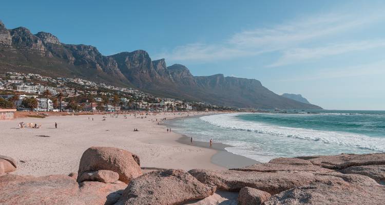 Plage de sable calme avec des vagues douces et chaîne de montagnes en arrière-plan sous une lumière douce de l'après-midi