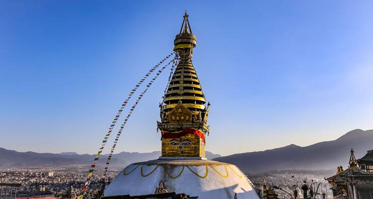 Das ikonische Swayambhunath-Stupa mit bunten Gebetsfahnen, die gegen einen kristallklaren blauen Himmel über dem Kathmandu-Tal flattern.
