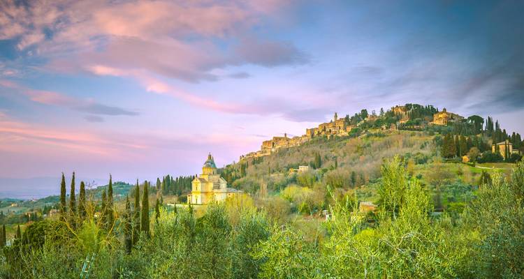 Montepulciano, une charmante ville toscane baignée de soleil, entourée par un paysage vallonné verdoyant et un ciel aux teintes pastel
