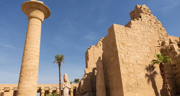 Las columnas de arenisca que se elevan y los muros erosionados del Templo de Karnak se alzan hacia un cielo azul brillante en Luxor.