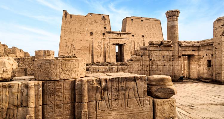Los enormes pilones de arenisca y los relieves intrincadamente tallados del Templo de Edfu se alzan contra un cielo azul brillante.